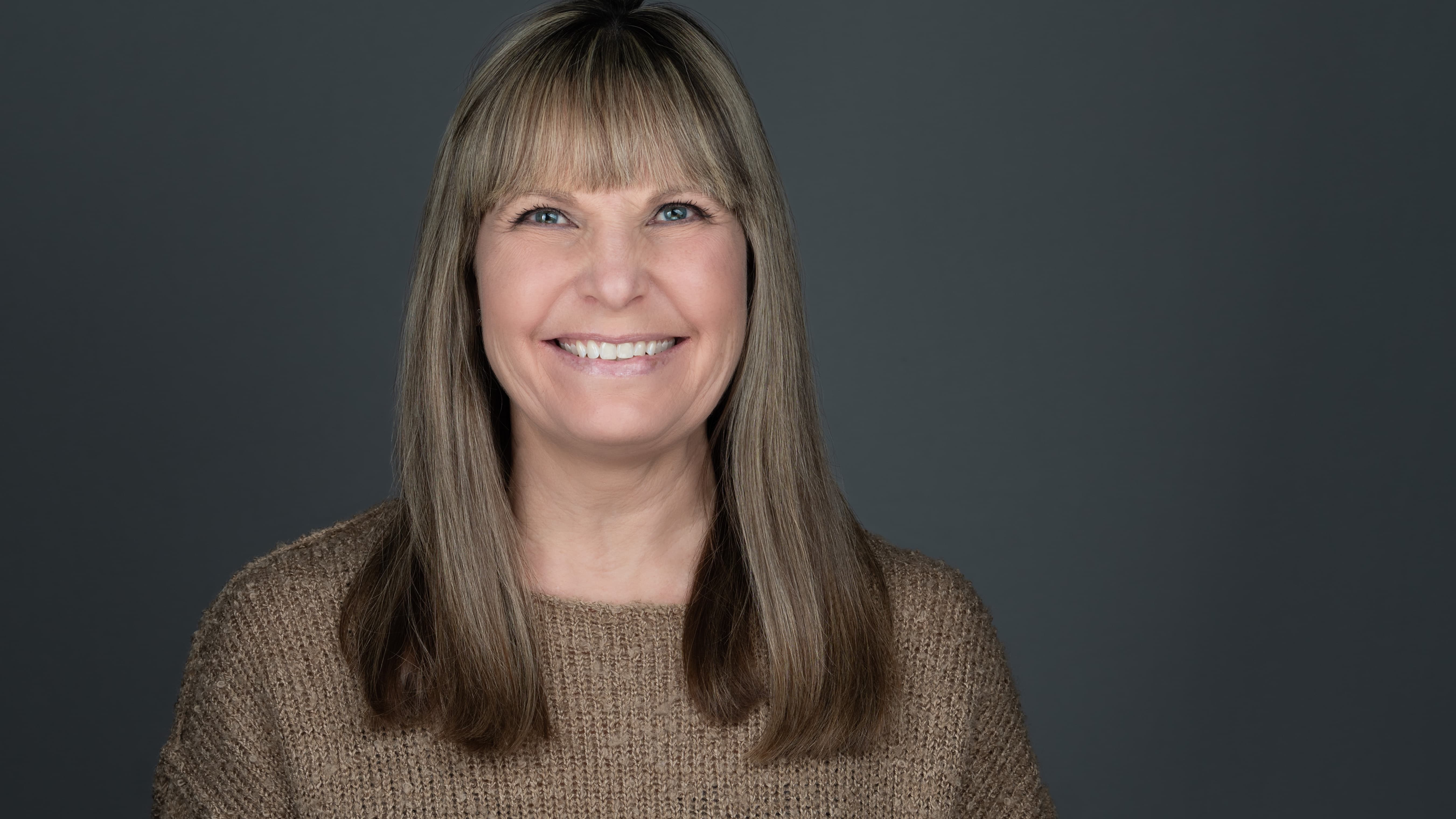 professsional headshot of women in brown sweater