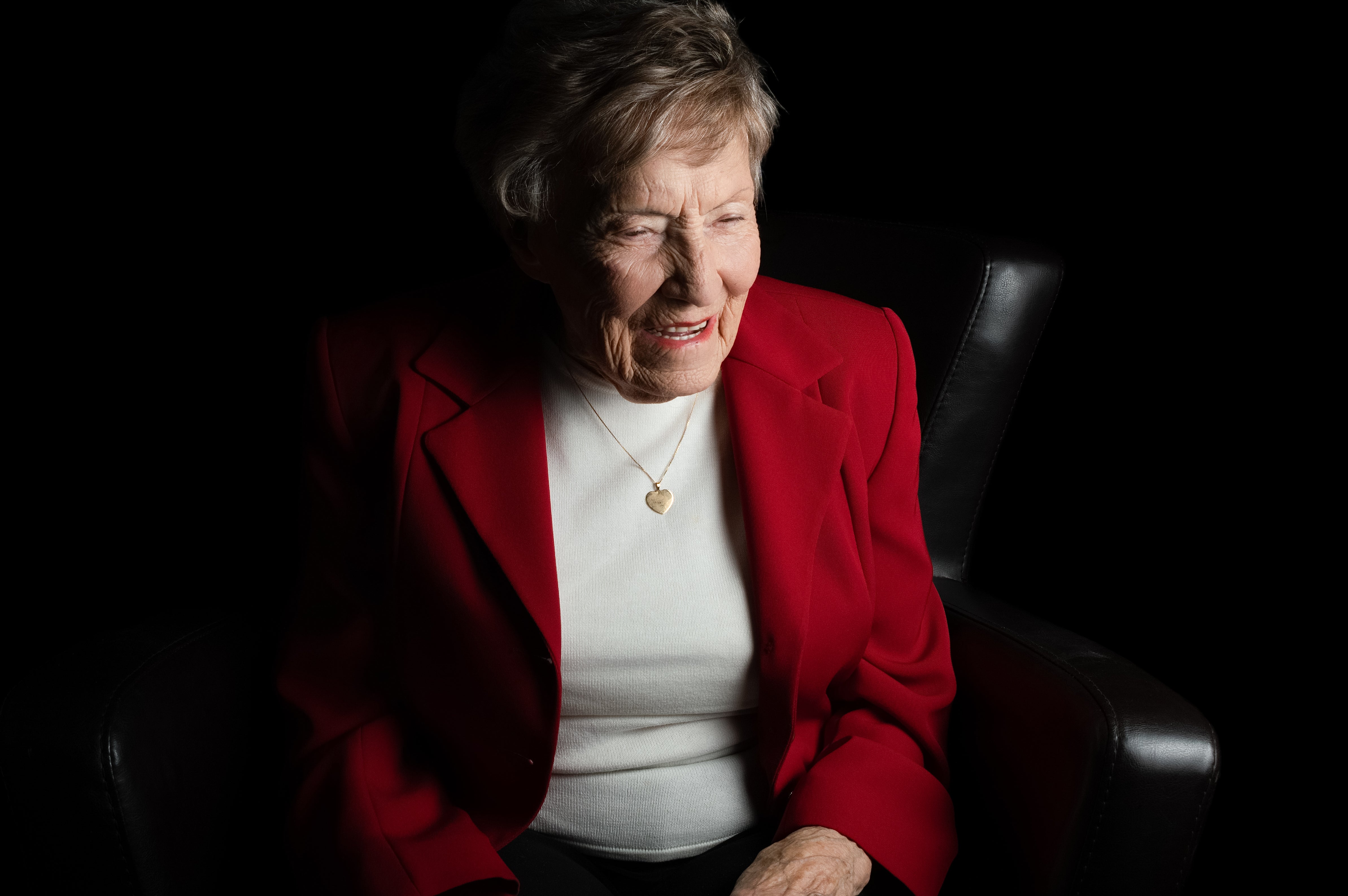 Woman in a red blazer sitting in a dark room