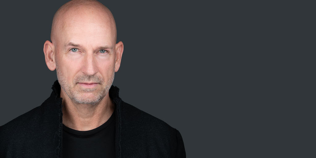 professional headshot of bald man on a gray background