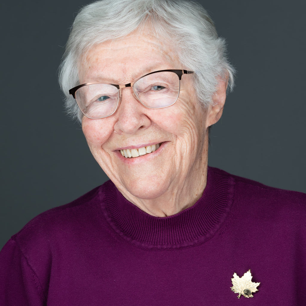 professional headshot of an elderly women wearing glasses and purple top